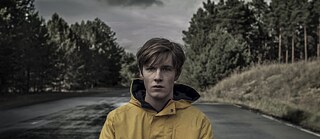 Jonas Kahnwald ( gespielt von Louis Hofmann) steht einsam und allein auf einer weiten Strasse