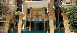Grünes Eingangstor vor einem sandfarbenem Gebäude, der Modern English School Cairo