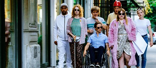 The Goldfish - film still: a group of people, colourfully dressed, walk along a pavement