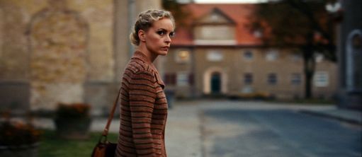 Frau mit Handtasche steht an einer Straße 