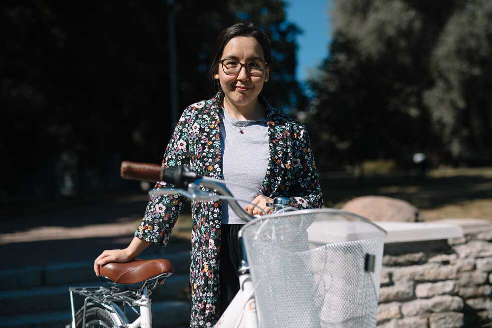 Eine dunkelhaarige junge Frau mit ihrem weißen Fahrrad.