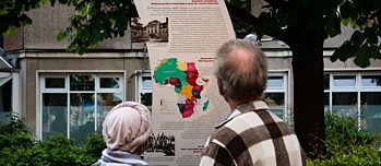 Dos personas en Berlín delante de una placa conmemorativa de la Conferencia del Congo:  más de cien años después de los crímenes cometidos por el poder colonial alemán en lo que hoy es Namibia, el gobierno federal reconoce los actos violentos contra los hereros y los nama. 