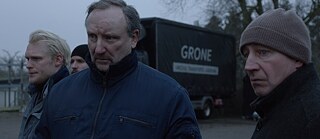 Vier Männer mit winterlicher Kleidung stehen vor einem LKW