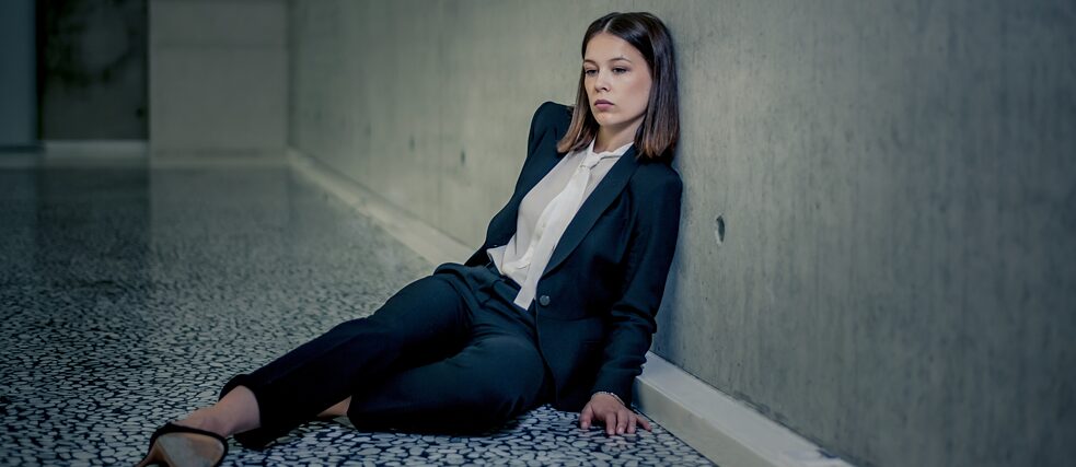 "Bad Banks": Jana Liekam (Paula Beer) sits exhausted on the floor in a large, empty room. She leans against the barren concrete wall.