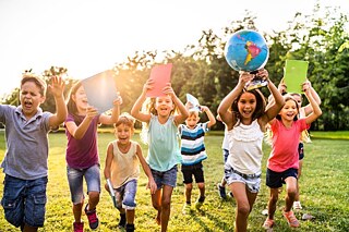 Kinder rennen mit Schulheften und einem Globus fröhlich über eine Wiese &copy; © Goethe-Institut Fortbildung Intensivtraining für Lehrende des Premier Degré  