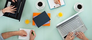 Tisch mit Tablet, Laptop und Händen