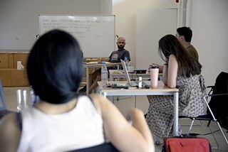 The picture was taken over the shoulder of one of the participants. You can see two other participants from the side. The fourth participant has turned his face to one of the other participants and is listening intently.