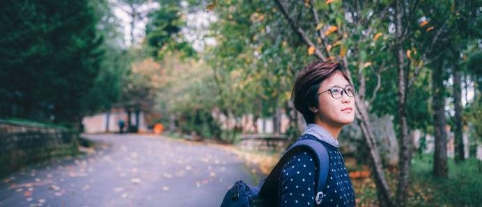 A young female graffiti artist, seen only from behind,  is painting a large colorful jungle mural