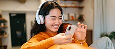A young woman with headphones and mobile phone is choosing a podcast