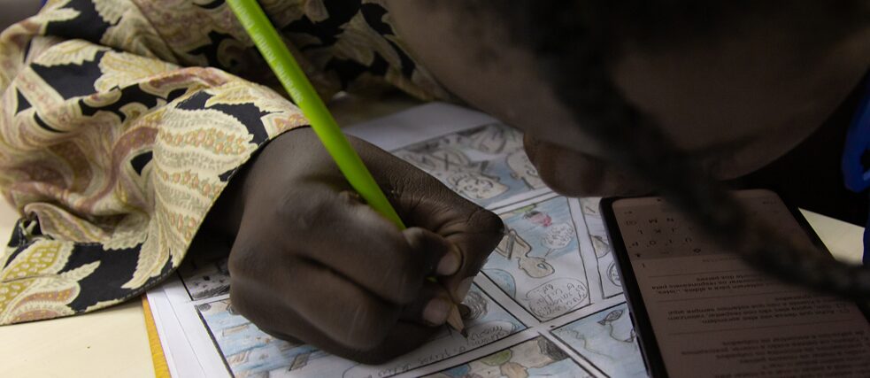 Une participante à un atelier écrit sur sa bande dessinée déjà colorée.