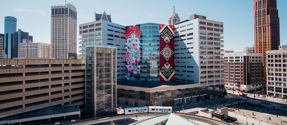 Il murale “Balancing Act” (sinistra) vicino a “Peace and Justice Lotus” (destra) su un complesso edilizio di Detroit, Michigan, USA.