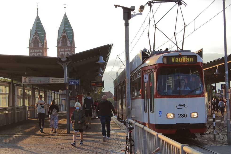 Eine Straßenbahn Richtung Vauban auf der Stühlingerbrücke, im Hintergrund die beiden Türme der Herz-Jesu-Kirche