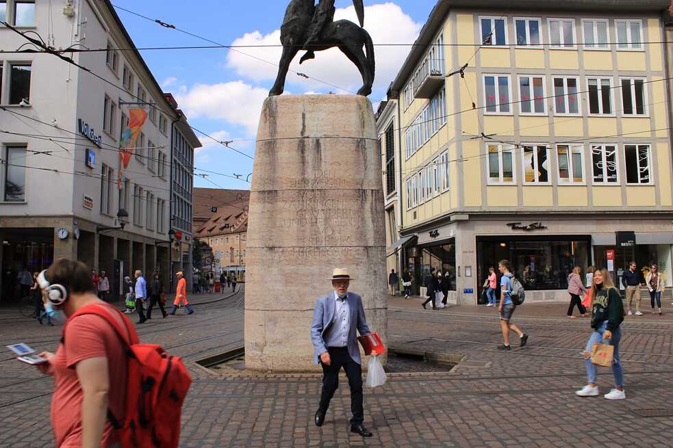 Fußgänger*innen gehen über die Straßenbahngleise in der Nähe des Bertoldsbrunnen