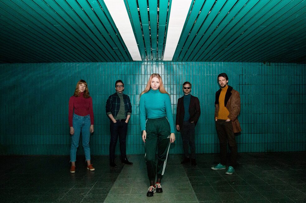 Eine Gruupe junger Musiker*innen steht im dunklen Flur. 