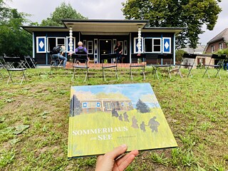 Das Buch Sommerhaus am See vor dem Haus, das Teil der Geschichte ist