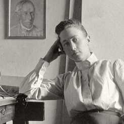 Resim siyah beyaz. Solda bir sandalyede oturan ve bir masaya yaslanmış bir kadın (Hilma afKlint) görülüyor. Odada kadının arkasında bir portre var.