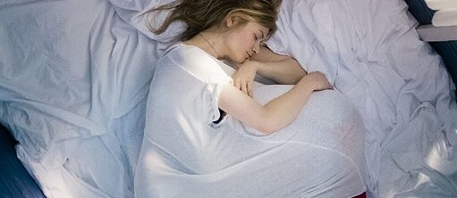 Junge Frau mit liegt schlafend im Bett.