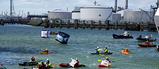 Shell s'est fixé pour objectif de devenir carboneutre d'ici 2050 - mais le groupe ne veut pas pour l'instant abandonner ses activités pétrolières et gazières, et mise sur la compensation et le stockage de CO2. Des militants de Greenpeace manifestent en octobre 2021 à Glasgow contre l'exploitation des combustibles fossiles avec des affiches arborant le slogan « Fossil free revolution ».