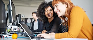2 Frauen vor einem Bildschirm sitzend
