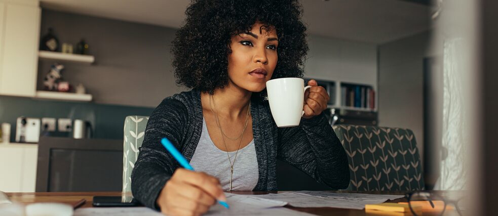 Eine Lernerein mit einer Kaffeetasse und einem Stift vor einem Laptop
