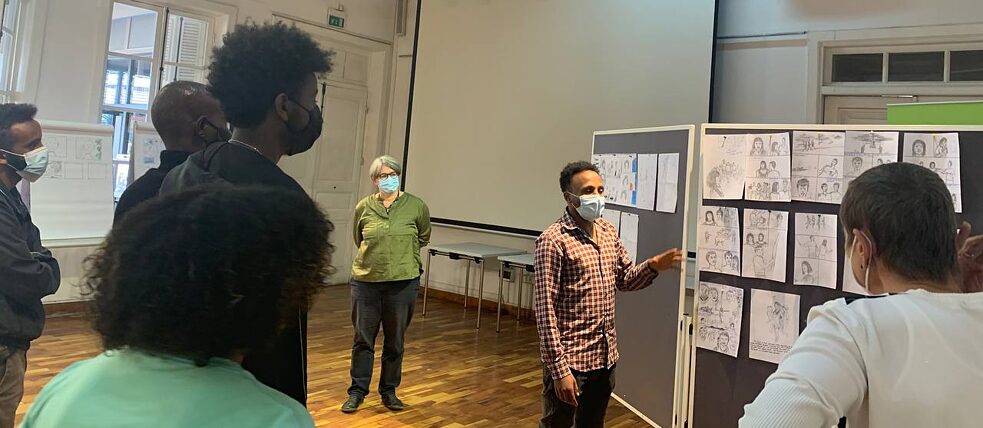 Um participante do workshop apresenta os seus painéis de banda desenhada ao grupo.