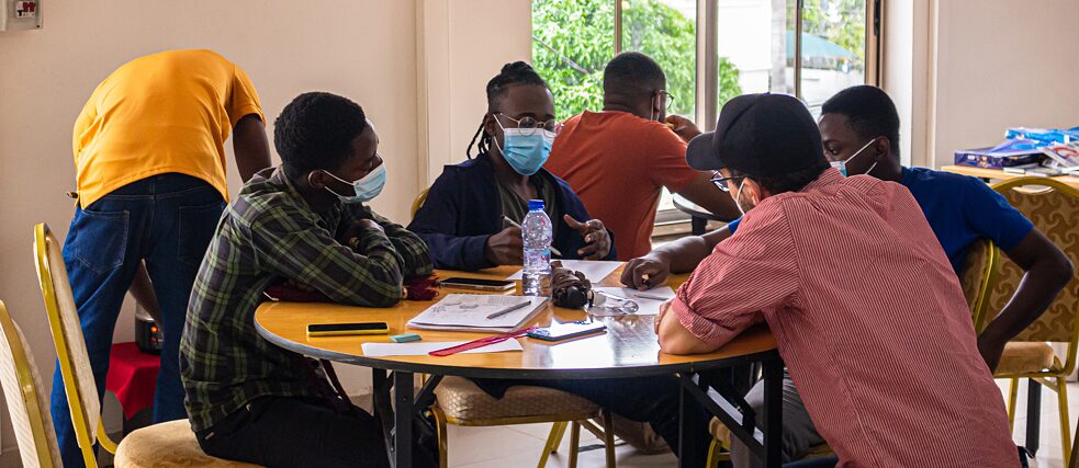 Plusieurs participants à l'atelier s'assoient à une table et discutent ensemble avec un formateur.