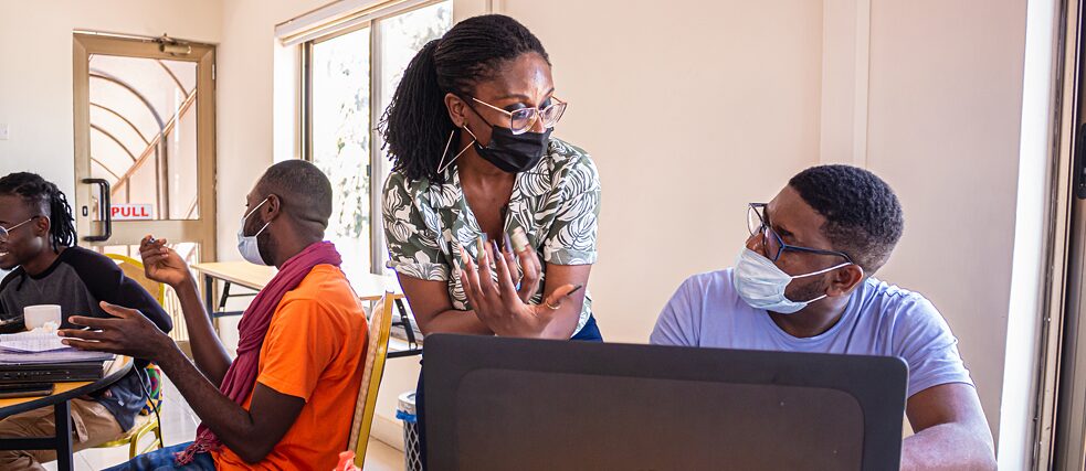 Les formateurs de l'atelier en conversation avec un participant à l'atelier.