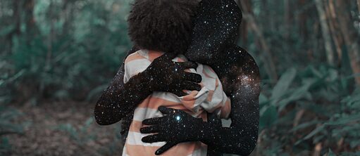 Im Hintergrund des Bildes befindet sich ein Wald. Vorne sieht man ein Kind von hinten. Dieses trägt ein gestreiftes Oberteil und hat einen Afro. Dieses wird umarmt von einer schwarzen Menschlichen Silhouette. Auf dieser Silhouette sind Galaxien abgebildet.