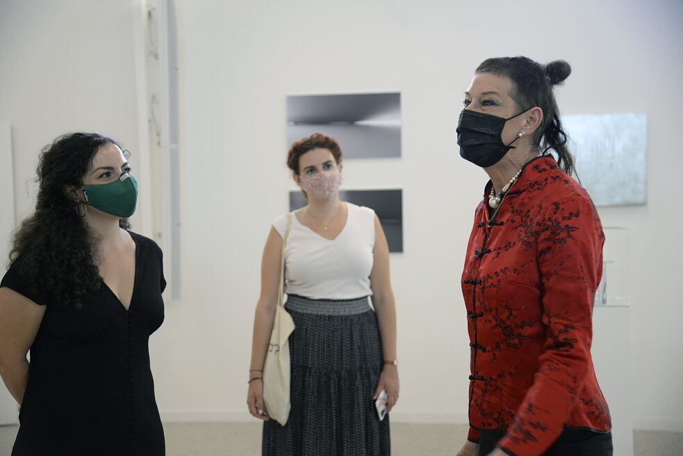 The picture shows three women talking to each other. In the background you can see different works of art.