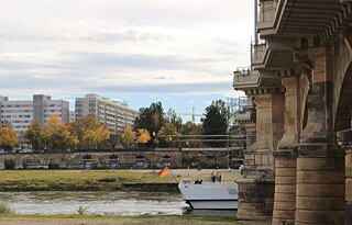 Ein Touristenboot mit deutscher Flagge fährt unter der Albertbrücke hindurch