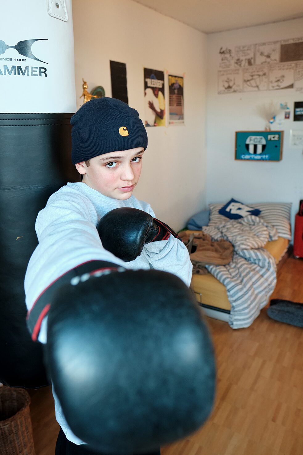 Le garçon porte des gants de boxe et montre un bras de boxe à la caméra