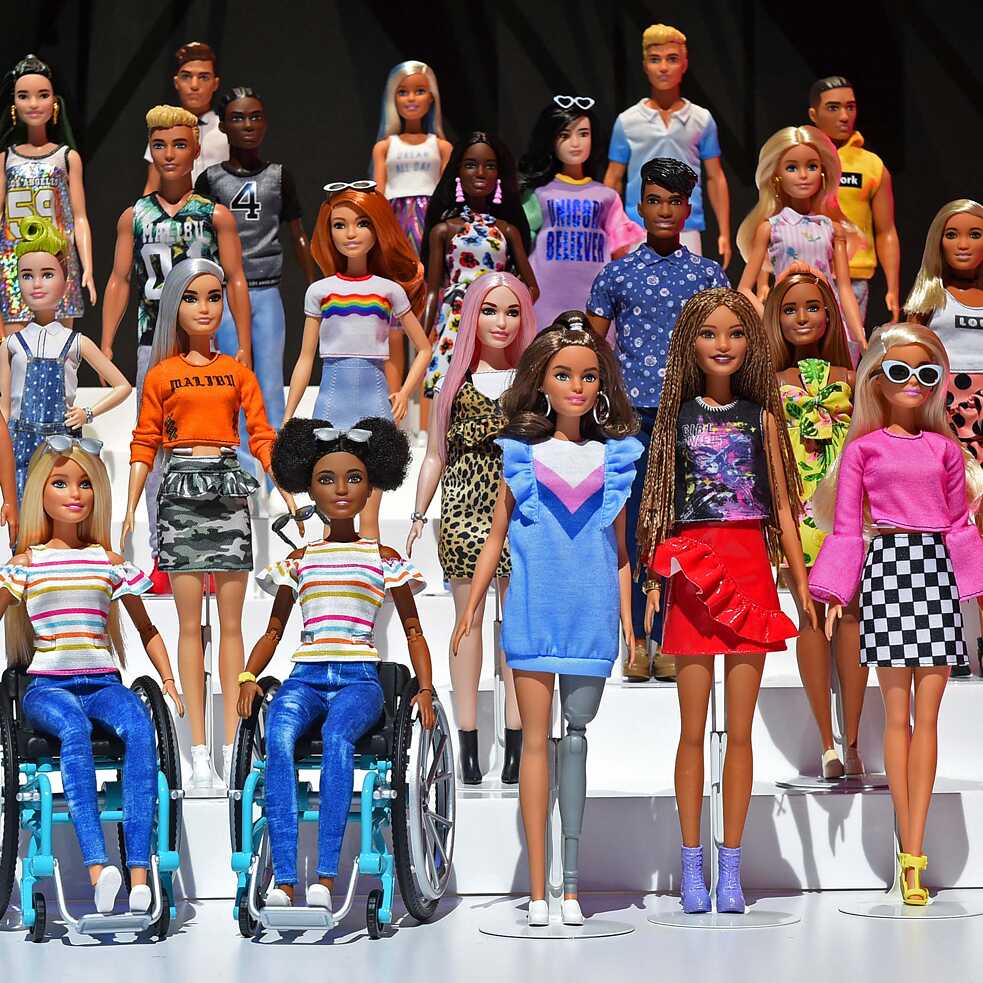 Many diverse toy barbies against black background