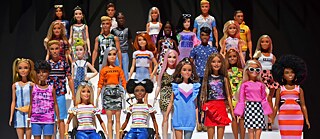 Many diverse toy barbies against black background