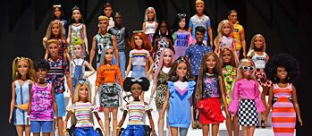 Many diverse toy barbies against black background