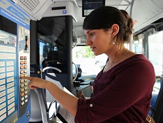 Die junge Frau Nevin steht an einem Fahrkartenautomaten im Bus