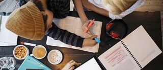 Ein Schüler sitzt an einem Tisch mit seiner Lehrerin und bearbeitet einen Text mit einem bunten Marker.