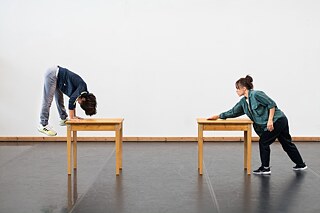 Foto von den Proben zu Move, Morph and More. Zwei Tänzerinnen nutzen Tische akrobatisch im Tanz.