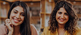 A young woman (Andri Christophides) with straight brown hair and a peach shirt sits in front of a table and smiles at the camera. Her elbows are resting on the table and she is supporting her chin with her right hand. In the background, bookshelves can be seen blurred. A young woman (Nihal Soğancı) with long, brown wavy hair and a yellow jacket sits in front of a table and smiles at the camera. Her hands rest on the table.