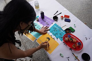 Miu Eng's daughter sketching a portrait of her mom at the <i>Dear Chinatown, DC: A poster making pop-up</i>, October 2021. 