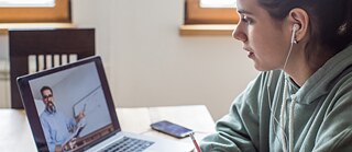 Frau vor Laptop sitzend in einer Videokonferenz