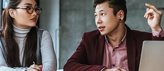 eine Frau und ein Mann vor einem Laptop sitzend