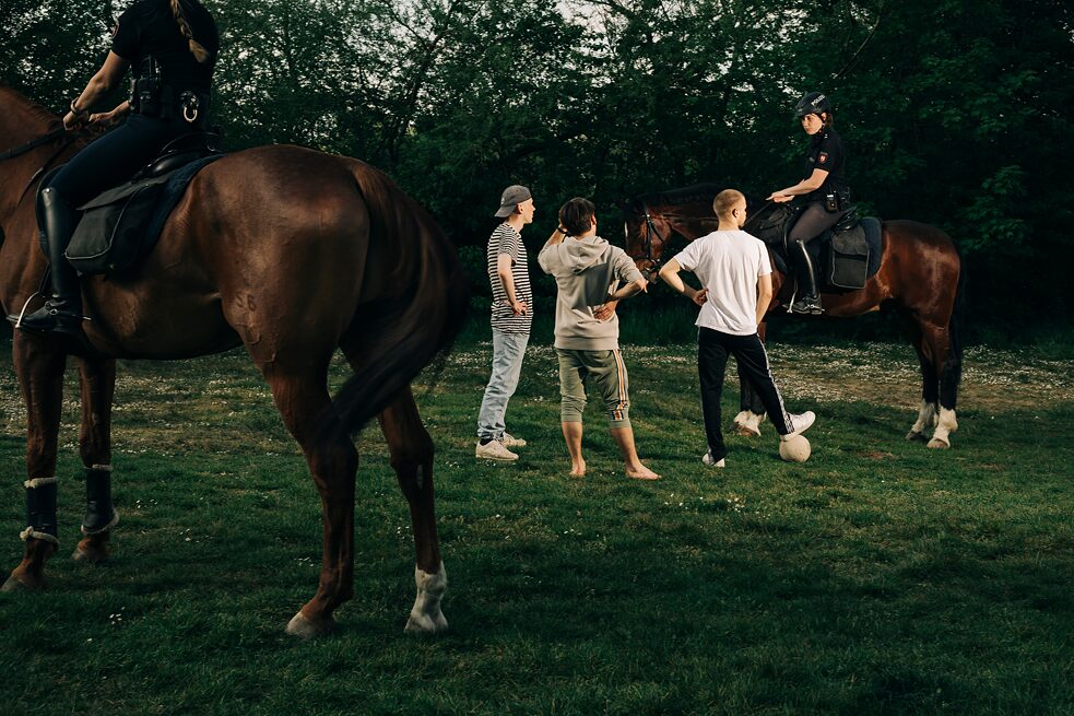 Mounted policewomen disperse three young men playing football in a park. In Germany it is forbidden at the time to be in public with more than two people if you do not belong to a family living in the same household. Photo taken: 27.04.2020, Hanover. 