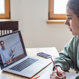 Frau vor Laptop sitzend in einer Videokonferenz