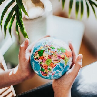 zwei Hände halten eine Weltkugel