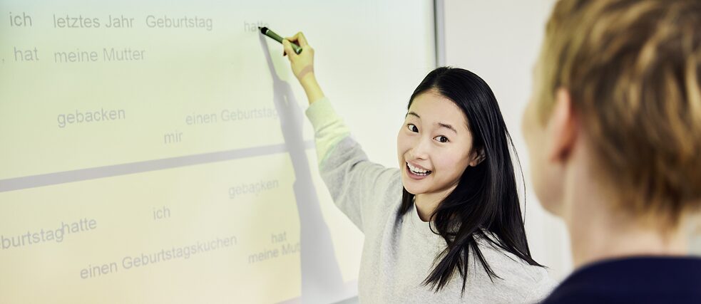 Lehrerin und Deutschlernerin vor einem Whiteboard