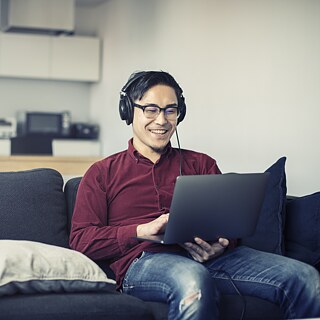 Mann mit Kopfhörern vor dem Laptop