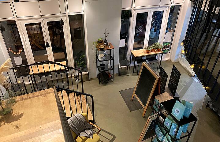 Café: picture from the second floor, a wooden staircase with black railing, high ceilings, modern, simple look.