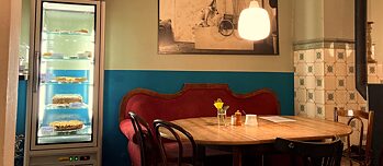 Ein Café, gemütliches Sofa in einer Ecke, davor ein Tisch mit Stühlen