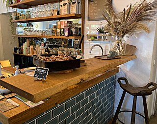 Wooden counter on which stands a tray with vegan cinnamon buns, behind it a bar