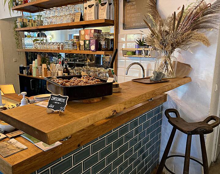 Wooden counter on which stands a tray with vegan cinnamon buns, behind it a bar